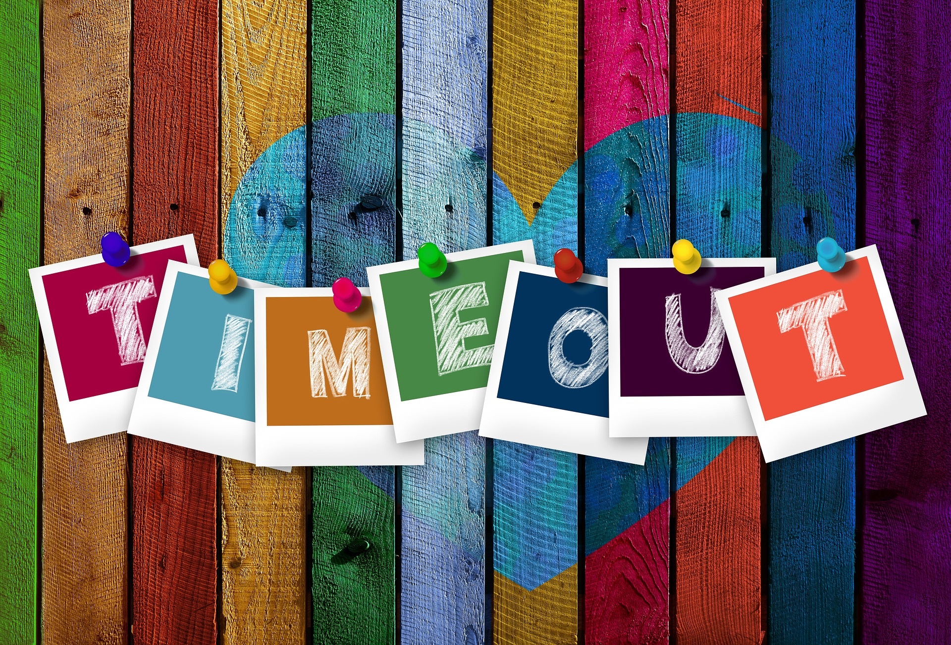 Bunt bemalter Bretterzaun mit angehefteten Buchstaben, die das Wort Timeout bilden.